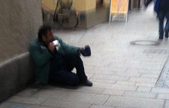 Bettler, der in der Fußgängerzone am Boden sitzt