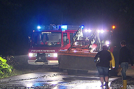 Feuerwehrauto mit Baggerfahrzeug in der Nacht bei Unwettereinsatz