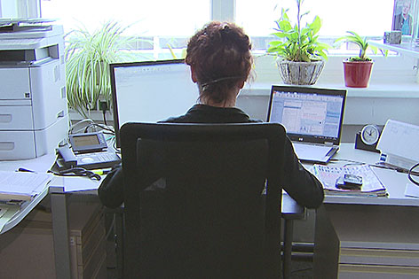 Frau sitzt im Büro am Schreibtisch vor dem Computer