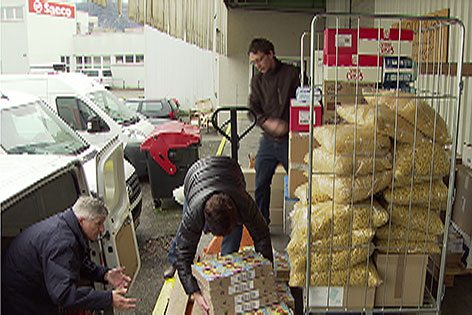 Leute räumen Lebensmittel aus einem Lastwagen in einen Kleintransporter