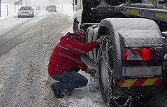 Lastwagenfahrer legt seinem Lkw Schneeketten an