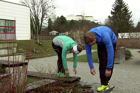 Doresia Krings und Michael Mayerhofer beugen den Rumpf bei überkreuzten Beinen.