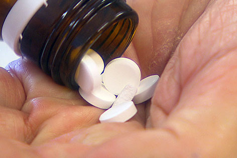 Tabletten werden aus Fläschchen in die Hand geschüttet