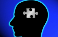 Abbild eines schwarz gefärbten Kopfes im Profil, mit einem Puzzlestück in der Mitte des Kopfes
