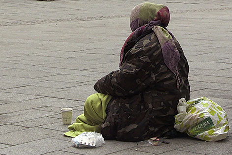 Bettlerin sitzt auf Straßenpflaster