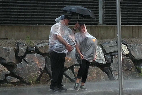 Pärchen mit Schirm im strömenden Regen eines Gewitters