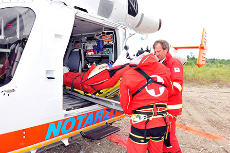Patient wird von Rettungsteam in Notarzthubschrauber geladen 