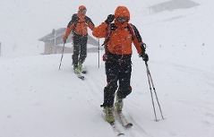 Bergretter bei Sucheinsatz im Schneetreiben im Winter vor Almhütten (Genneralm, Osternhorngruppe)