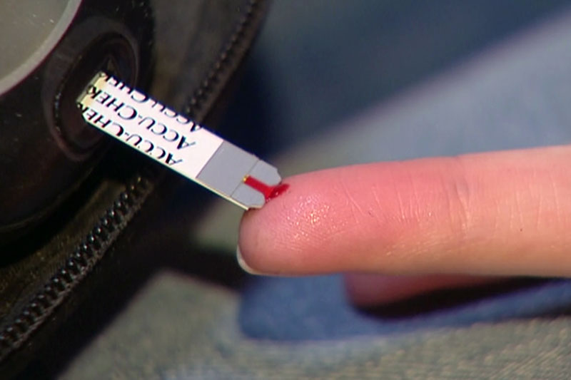 Bluttest bei Diabetiker am Finger mit Blutstropfen