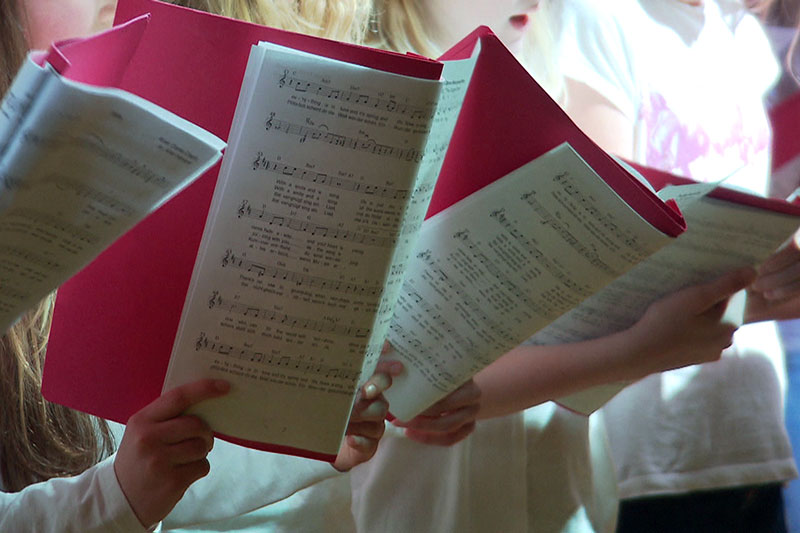 Kinderchor mit Notenmappen beim Singen