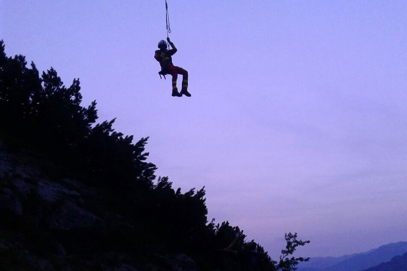 Flugretter hängt am Rettungstau eines Notarzthubschraubers in Bergen in der Abenddämmerung
