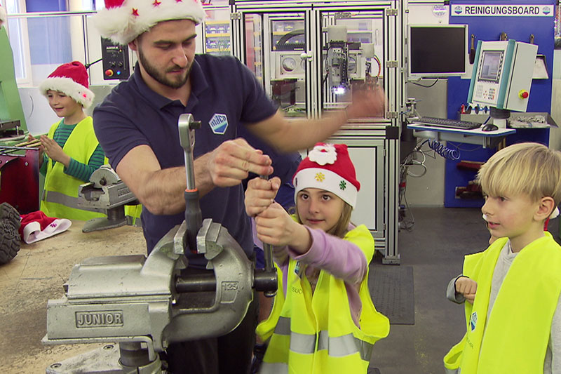 Kinder mit Weihnachtsmützen in Werkstatt des Beschlägeherstellers MACO in der Stadt Salzburg