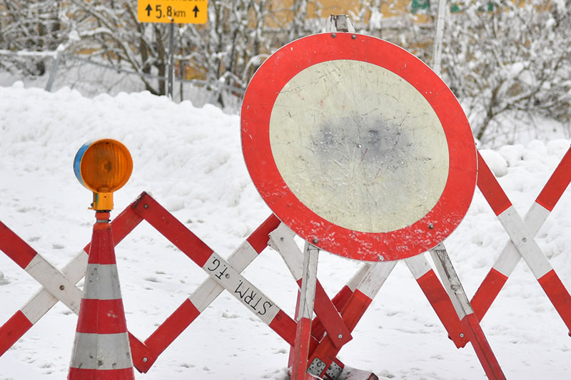 Scherengitter und Fahrverbotsschild auf Schneefahrbahn für Straßensperre / Lawinensperre