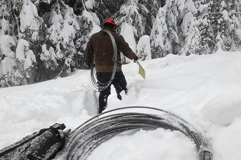 Techniker der Salzburg Netz GmbH im Schnee mit Draht für Stromleitungen