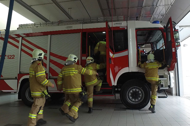 Feuerwehrleute steigen in Einsatzfahrzeug (Feuerwehrauto)